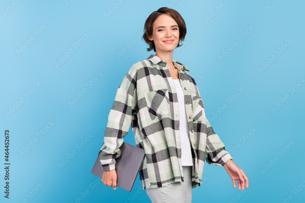 Photo of nice young brunette lady hold laptop wear plaid shirt isolated on blue color background Photo of nice young brunette lady hold laptop wear plaid shirt isolated on blue color background