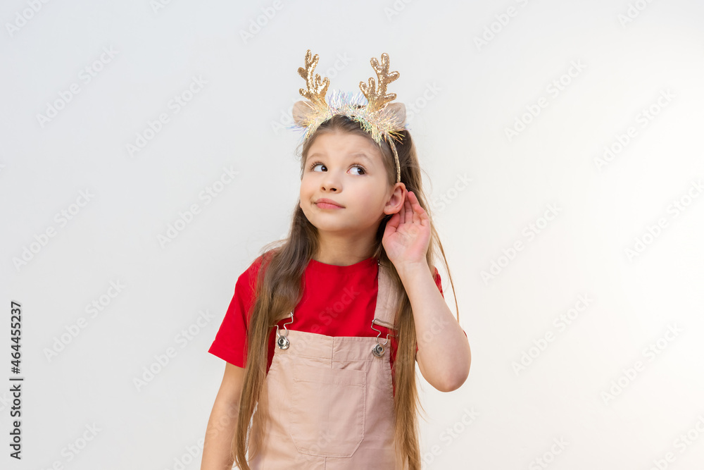 A little girl in Christmas reindeer horns is eavesdropping on you. A little girl in Christmas reindeer horns is eavesdropping on you.
