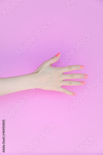hand showing number five In front of the pink background