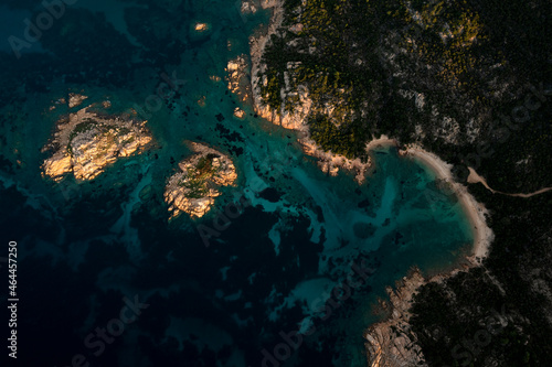 View from above, stunning aerial view of a green and rocky coast with a beach bathed by a turquoise sea during a beautiful sunrise. Capo Ceraso, Sardinia, Italy.