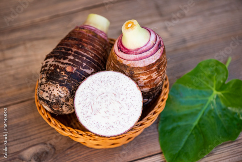 Taro root with slice half on basket and taro leaf and wooden background, Fresh raw organic taro root ready to cook