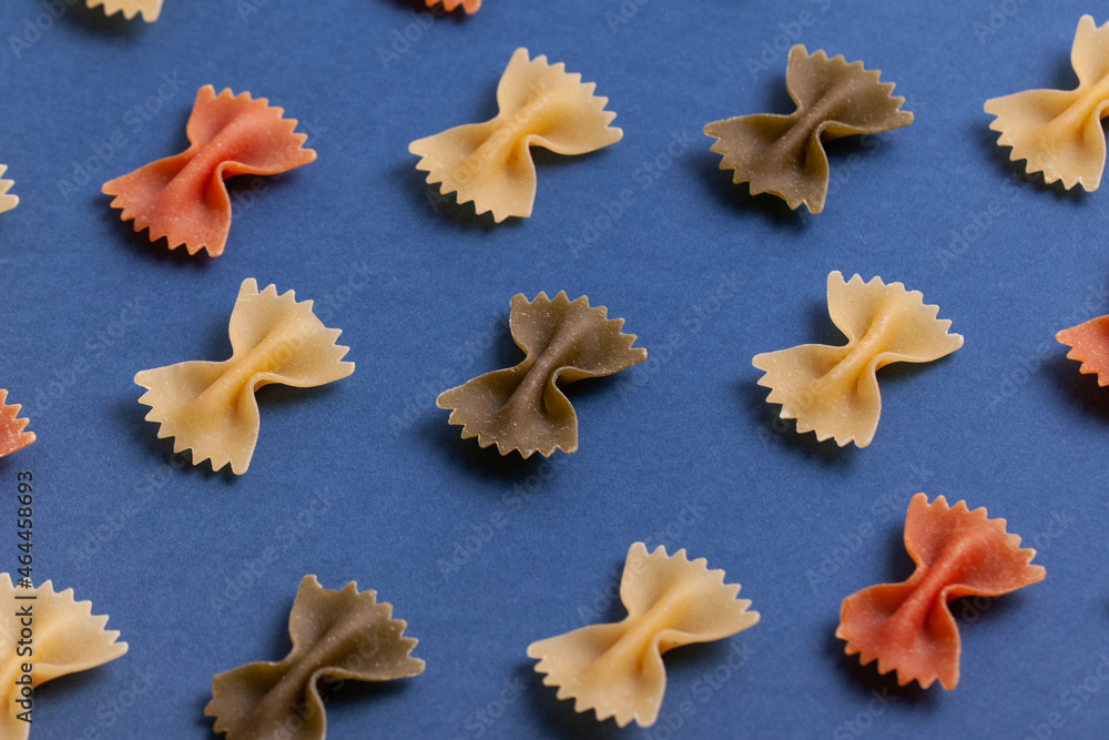 Pattern made of uncooked farfalle pasta on dark navy background. Macaroni background. Top view, flat lay. Pattern made of uncooked farfalle pasta on dark navy background. Macaroni background. Top view, flat lay.