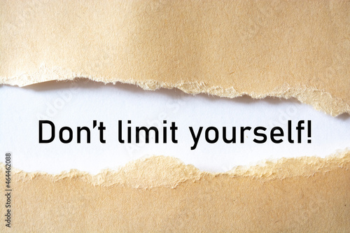 Don't limit yourself. words. text on brown paper on torn paper background.