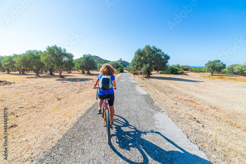 Woman riding MTB in Maremma nature reserve, Tuscany, Italy. Cycling among extensive pine forest olive trees and green woodland in natural park, dramatic coast