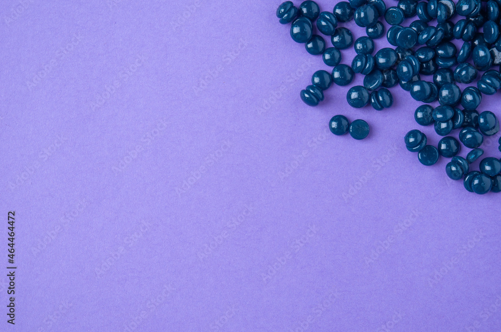 Granules of wax for depilation on purple background. Copy space. Granules of wax for depilation on purple background. Copy space.