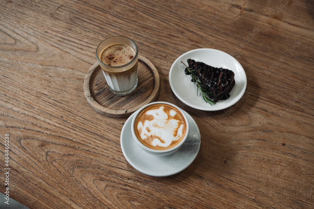 Obraz premium Latte art coffee on wooden table in coffee shop