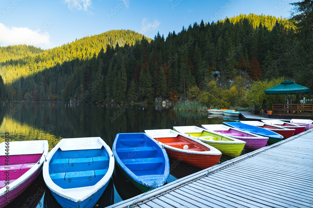 Boats on the lake. The reflection of the forest in the lake water. Colorful boats on the Red Lake, Romania Boats on the lake. The reflection of the forest in the lake water. Colorful boats on the Red Lake, Romania