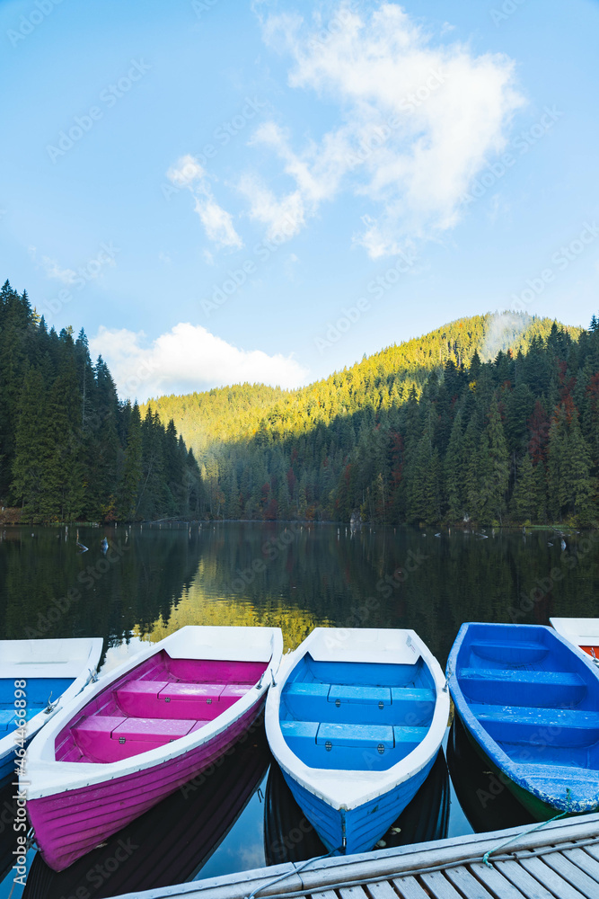 Boats on the lake. The reflection of the forest in the lake water. Colorful boats on the Red Lake, Romania Boats on the lake. The reflection of the forest in the lake water. Colorful boats on the Red Lake, Romania