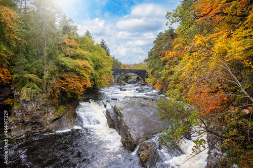 The beautiful Invermoriston Falls during autumn time with golden leaves and sunlight, Highlands, Scotland