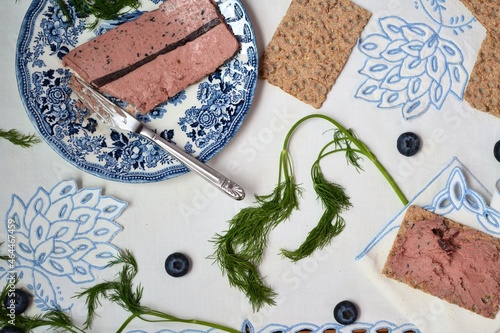 Fototapeta Naklejka Na Ścianę i Meble -  Terrine or pate with blueberries surrounded by toast on an embroidered tablecloth