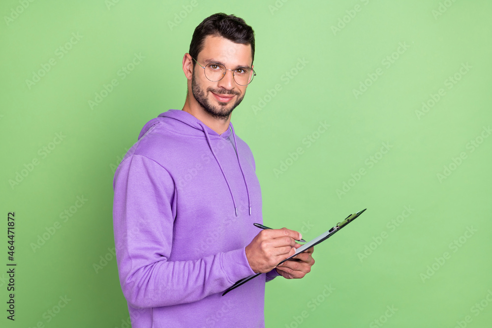 Profile photo of nice young brunet guy write paper wear spectacles hoodie isolated on green color background Profile photo of nice young brunet guy write paper wear spectacles hoodie isolated on green color background
