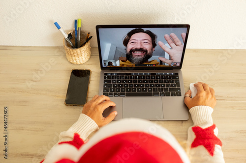 Woman at home in christmas holiday calling man using laptop computer on line video call communication. People and ommunication technology in festive winter season photo