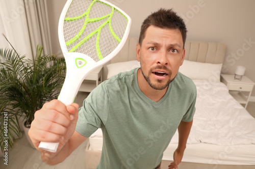 Bilde på lerret Man with electric fly swatter in bedroom. Insect killer