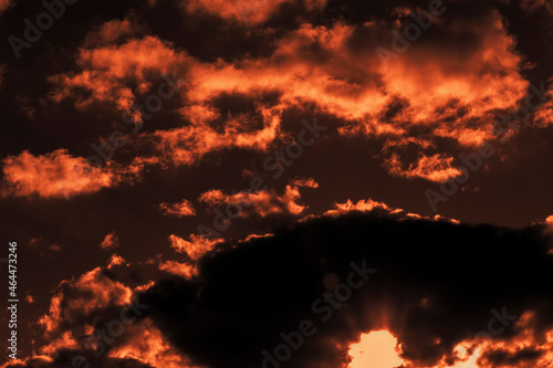 Sky with clouds in autumn at sunset of the day. The sun sat down in a thundercloud.  Light flares on the camera lens from the sun. Shooting against a light source. Selective focus. © Allgoo