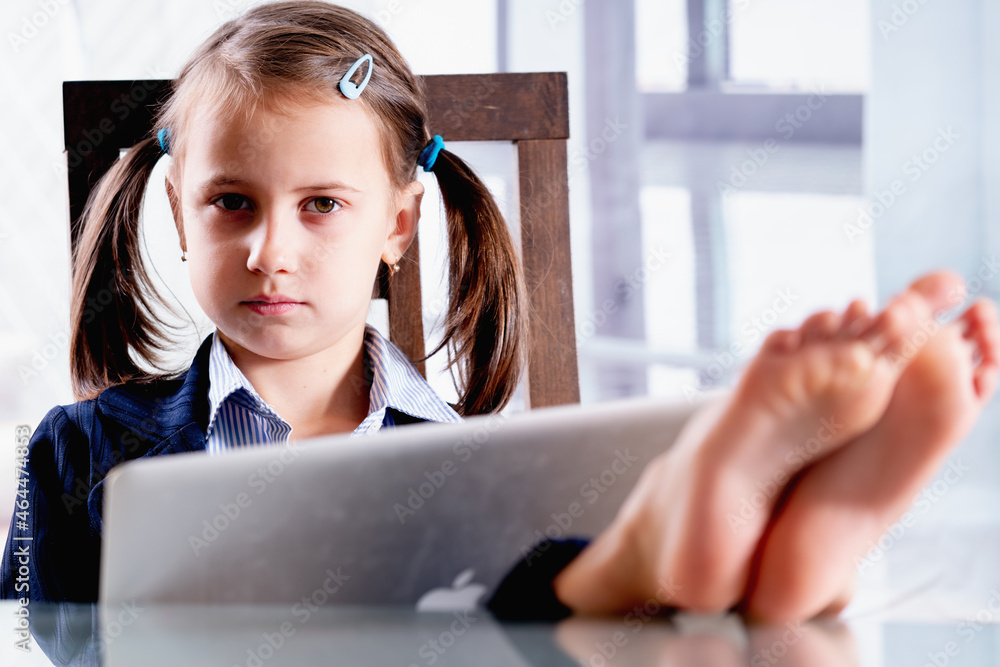 Humorous portrait of business child girl with bare feet on the table