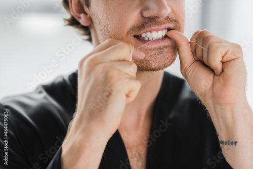 Quadro su tela Cropped view of man in black robe cleaning teeth with dental floss