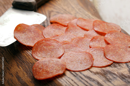 Slices of pepperoni salami on a wooden background