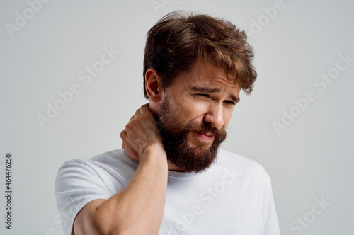 bearded man in a white t-shirt stress medicine pain in the neck isolated background