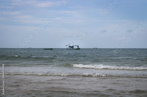 The fishing boat floats in the middle of the sea in the evening.