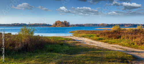 Autumn panorama with sandy road and blue lake