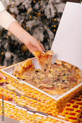 Vertical photo of a hand taking a slice of pizza. photo