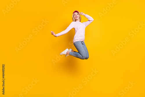 Photo of charming carefree young lady wear pink sweater headwear smiling jumping high isolated yellow color background © deagreez