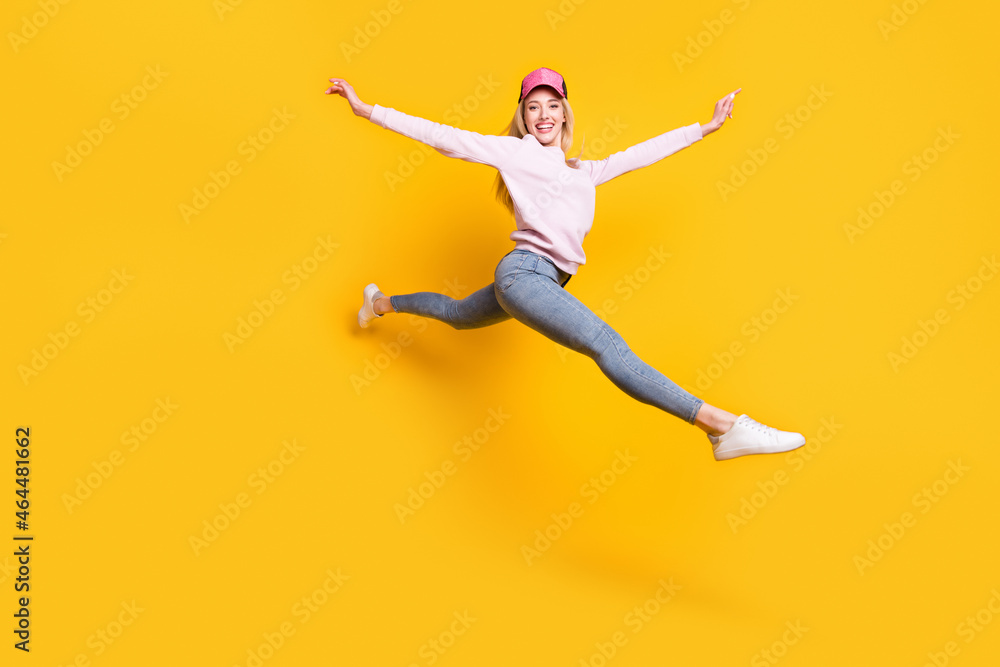 Photo of carefree shiny young lady wear pink sweater headwear smiling jumping high isolated yellow color background