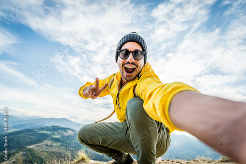 Young hiker man taking selfie portrait on the top of mountain - Happy guy smiling at camera - Hiking and climbing cliff