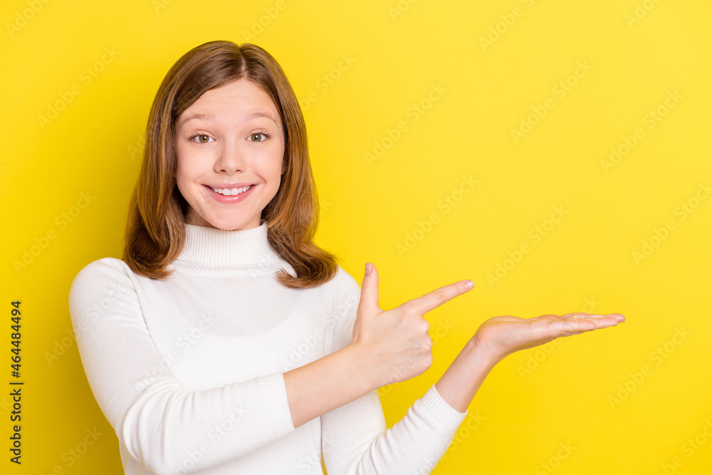 Photo of young girl happy positive smile point finger product promo offer suggest isolated over yellow color background Photo of young girl happy positive smile point finger product promo offer suggest isolated over yellow color background
