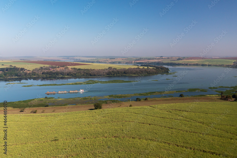 barge loaded with sugarcane ascending the Tietê-Paraná Waterway and planting sugarcane on the bank along the river