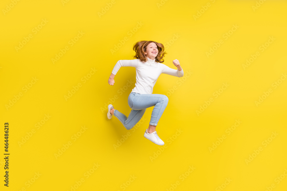 Full body photo of cheerful dreamy happy small girl jump up runner empty space isolated on yellow color background