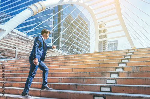 Young businessman walking in city for going to work with cityscape background. © Pornnarong