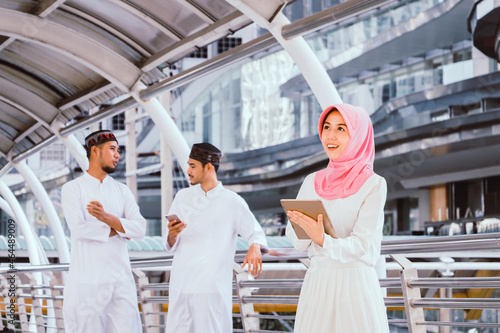 Portrait of muslim business woman standing and using tablet with cityscape background.