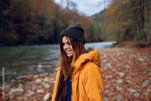 cheerful woman in a yellow jacket near the river autumn walk