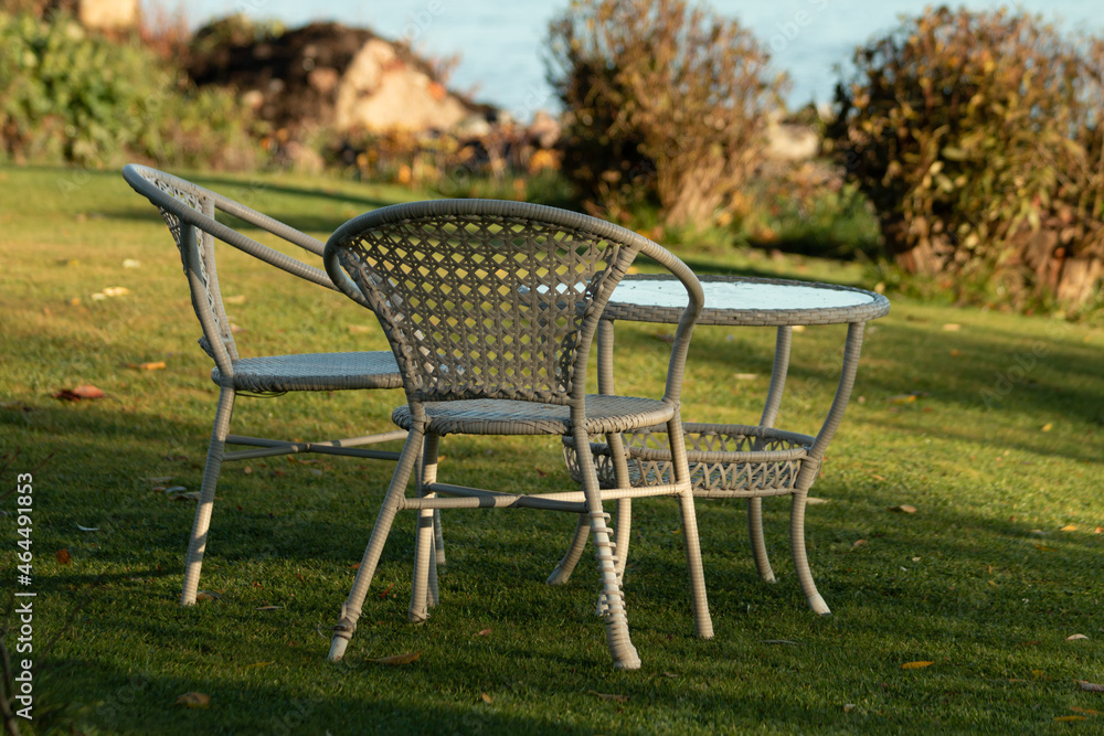 Wicker garden furniture in a green meadow by the sea. Plastic furniture