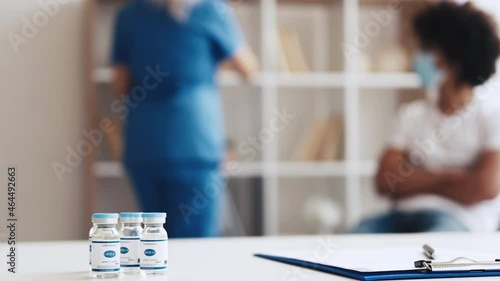 Coronavirus vaccine. Flu shot. Covid-19 prevention. Female doctor giving Arab male patient in face mask injection jab dose on defocused hospital background.