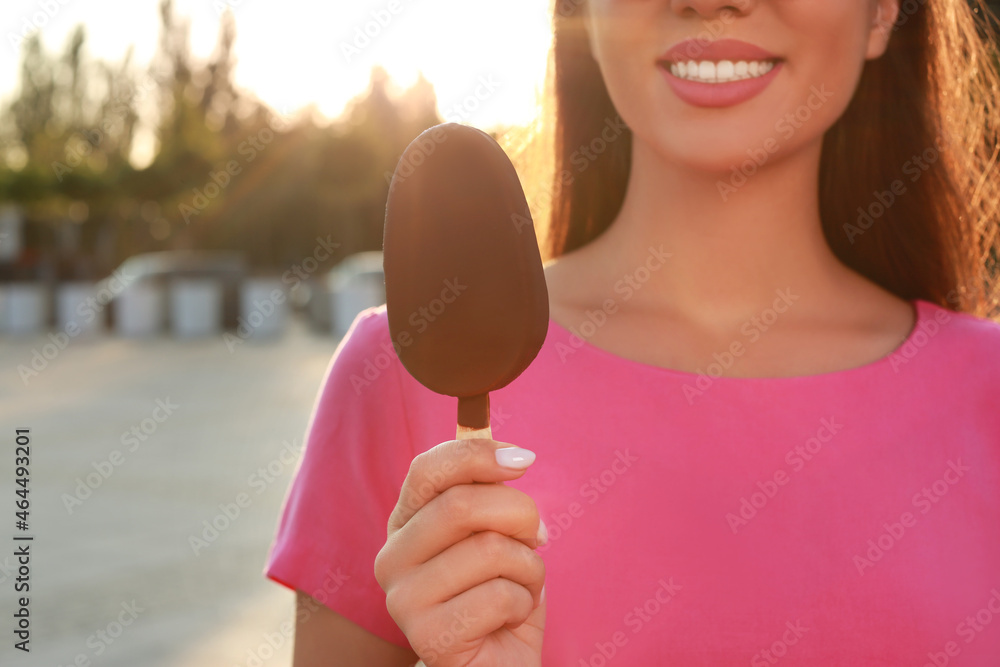Young woman holding ice cream glazed in chocolate on city street, closeup Young woman holding ice cream glazed in chocolate on city street, closeup