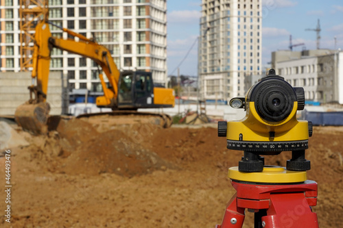 Fototapeta Naklejka Na Ścianę i Meble -  Photo of a level at the construction site of multi-storey buildings with a yellow excavator on the street in the city
