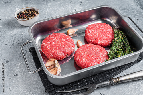 Fresh Raw Ground mince beef meat Hamburger steak patty in a steel tray. Gray background. Top view. Copy space