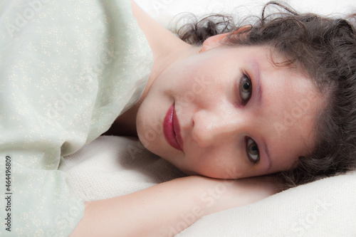 Close up beauty portrait of a beautiful young green eyed woman lying on her right side.