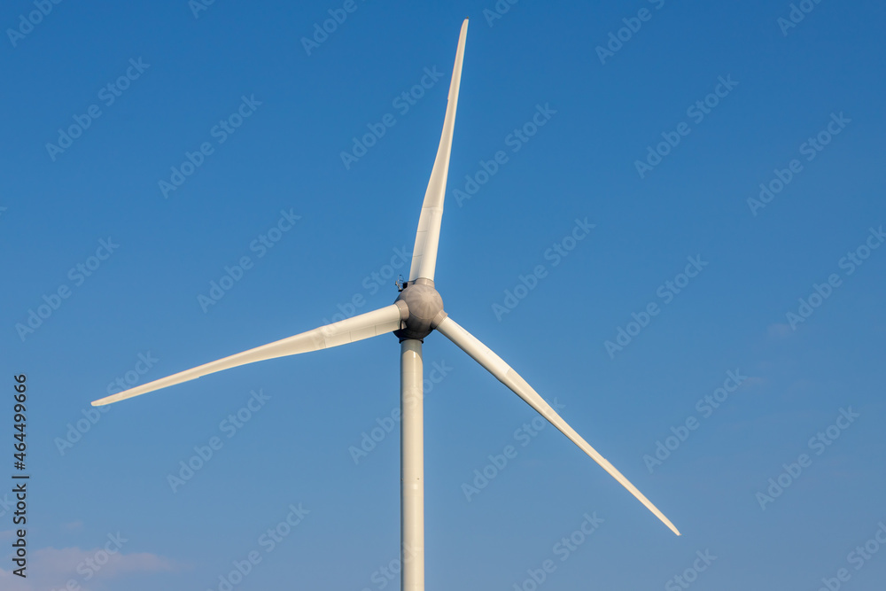 Selective focus of white wind turbine or alternatively referred to as a wind energy converter with blue sky and white fluffy clouds background, Clean energy, Wind farm in Netherlands. Selective focus of white wind turbine or alternatively referred to as a wind energy converter with blue sky and white fluffy clouds background, Clean energy, Wind farm in Netherlands.