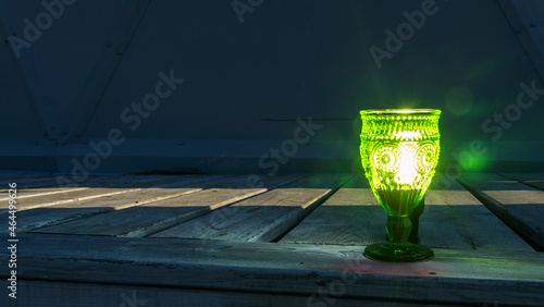 Illuminated empty glasses of green glass on a stem on a wooden background. Close-up view. © kalyanby