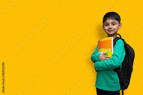 Child boy with book and bag on shoulders going to school concept copy space