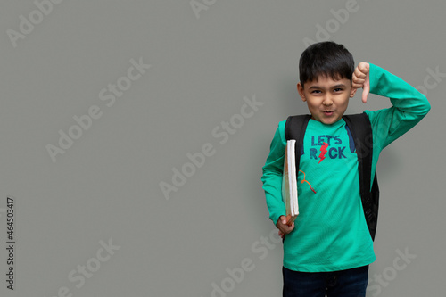 Sad child boy with books in hand and bag on shoulders, hate study concept copy space