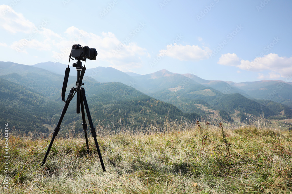 Tripod with modern camera in mountains on sunny day. Professional photography