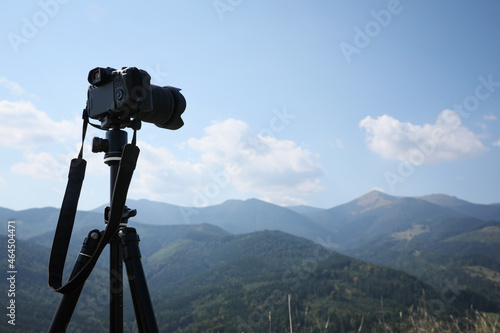 Tripod with modern camera in mountains on sunny day. Professional photography
