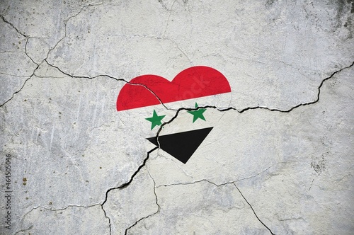 The symbol of the national flag of Syrian Arab Republic in the form of a heart on a cracked concrete wall.