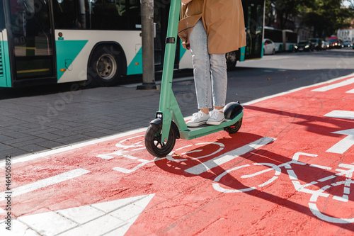 traffic, city transport and people concept - woman riding electric scooter along red bike lane with signs of bicycles and two way arrows on street