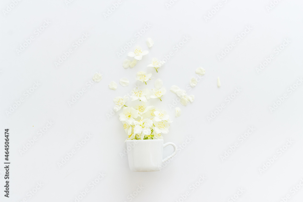 Jasmine flowers flying into a cup. Herbal tea concept