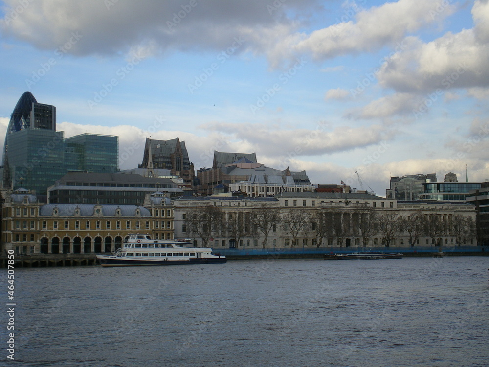 La ville de Londres avec ses bâtiments en pierre ou un peu en verre, avec une Tamise calme et plaine, ville sous un ciel bleu et avec un peu de nuages, vie et zone urbaine britannique